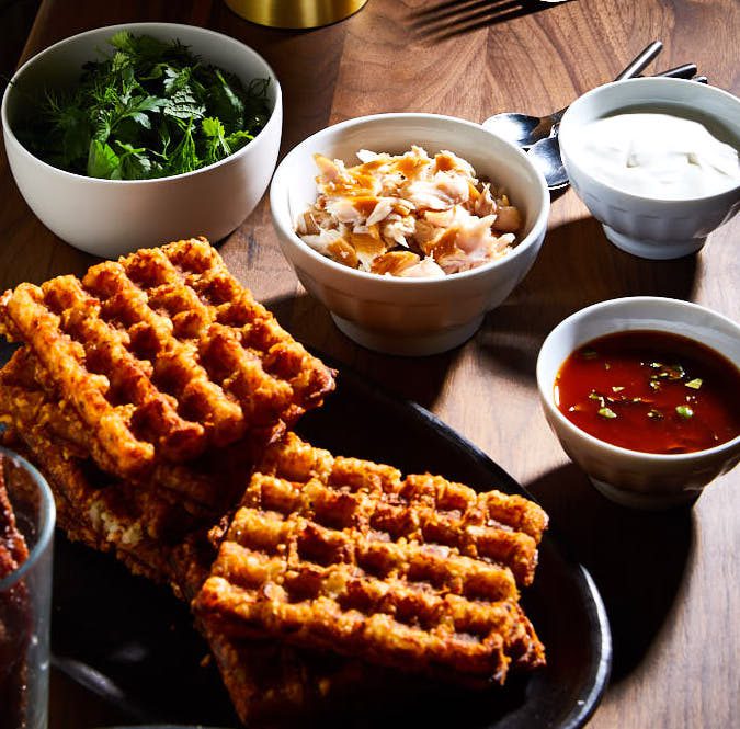 Tater Tot Waffles with Smoked Trout, Sour Cream, Chermoula, and Herb Salad